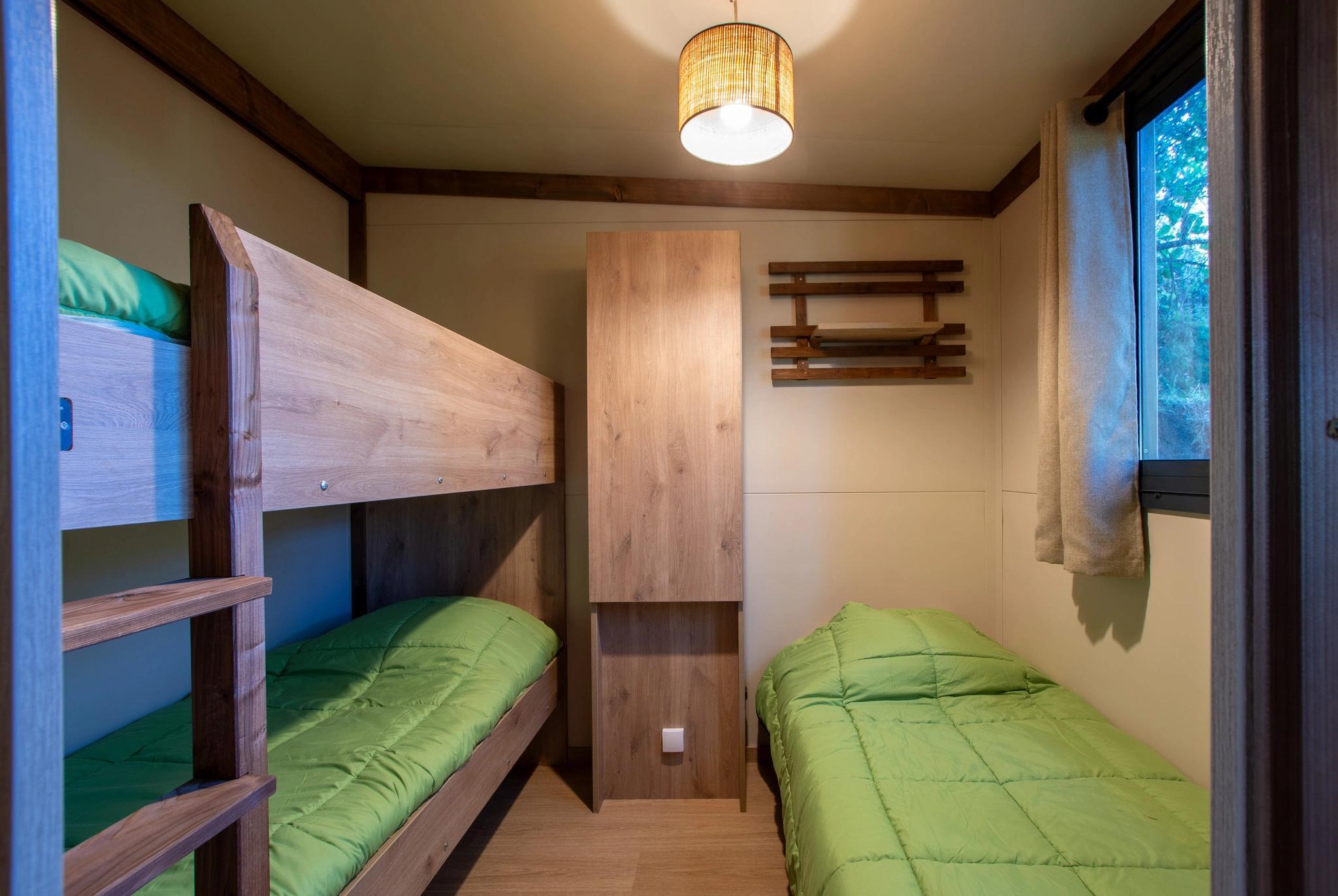 Chambre avec lits superposés et lit simple, idéale pour les enfants, dans un chalet du Camping Bavella Vista
